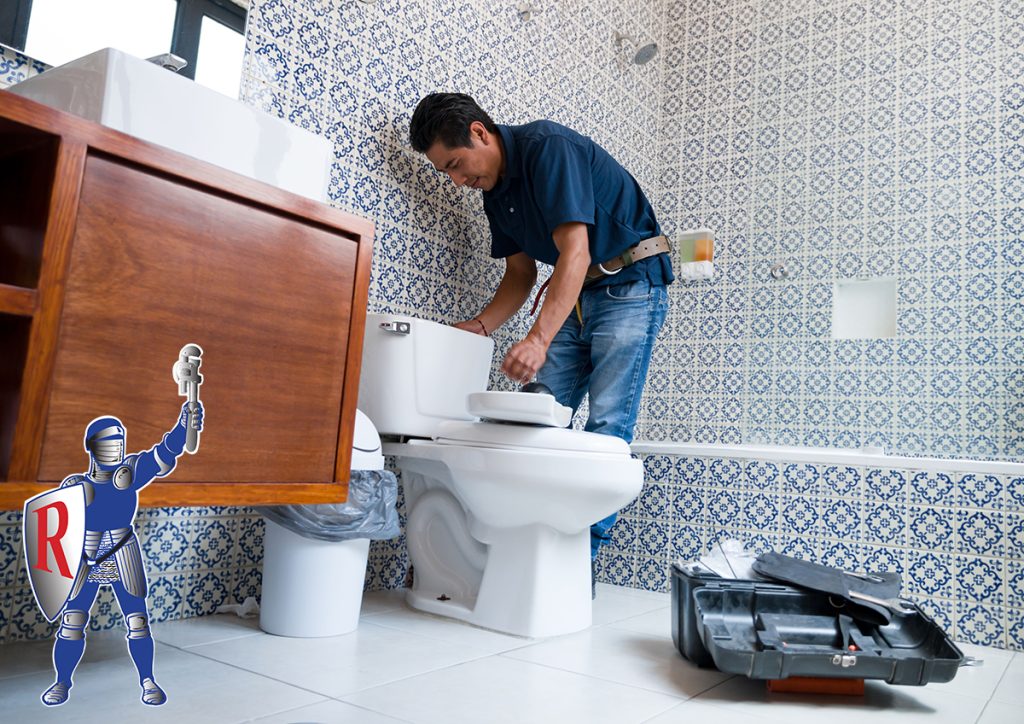 A professional, well-dressed plumber installing a new toilet in a bathroom remodel. The bathroom is well lit and the walls are lined with beautiful blue and white patterned tile.